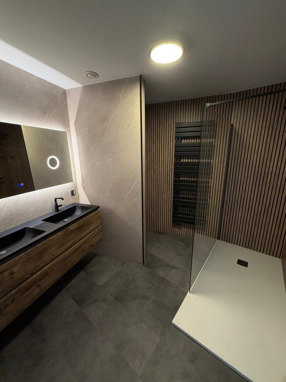 Moderne badkamer met houten wastafelmeubel, inloopdouche en houten lattenwand.