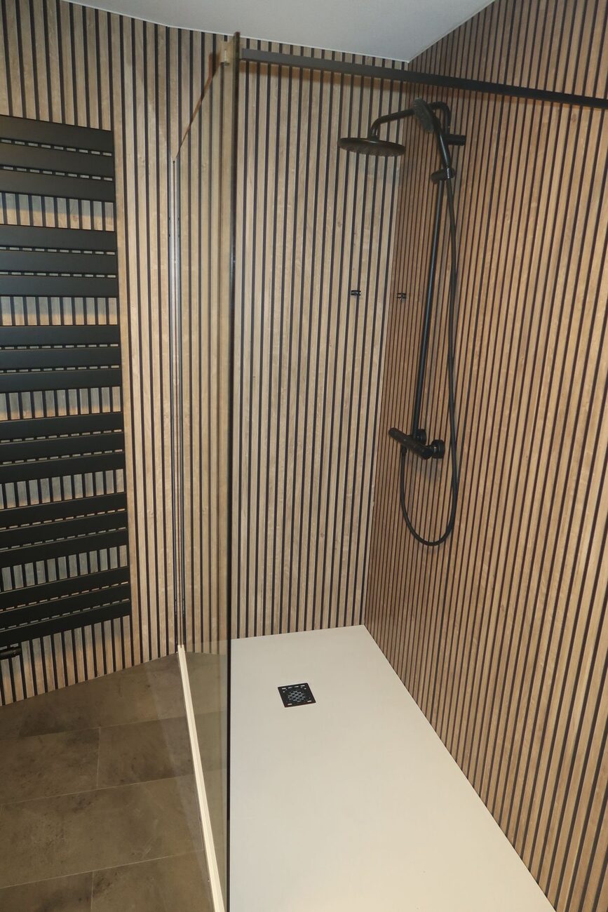 Moderne badkamer met houten lattenwand, inloopdouche en zwarte doucheset.