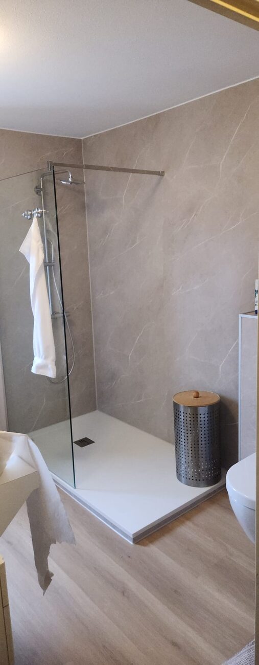 Moderne badkamer met inloopdouche, grijze wandtegels en houtlook vloer.