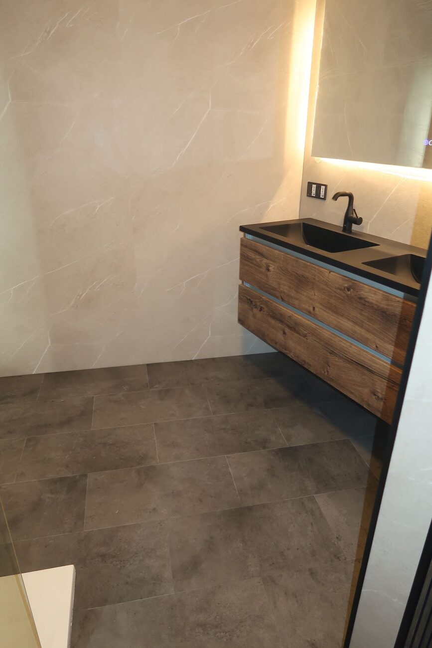 Moderne badkamer met houten wastafelmeubel en donkere vloertegels