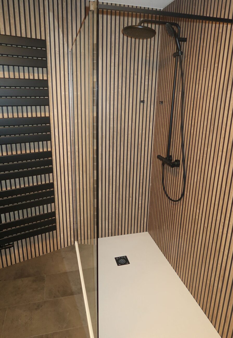 Moderne badkamer met houten lattenwand, inloopdouche en zwarte radiator