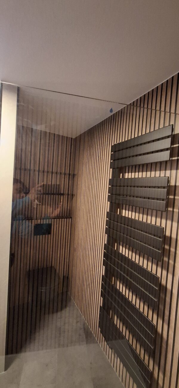 Moderne badkamer met houten lattenwand en donkere handdoekradiator