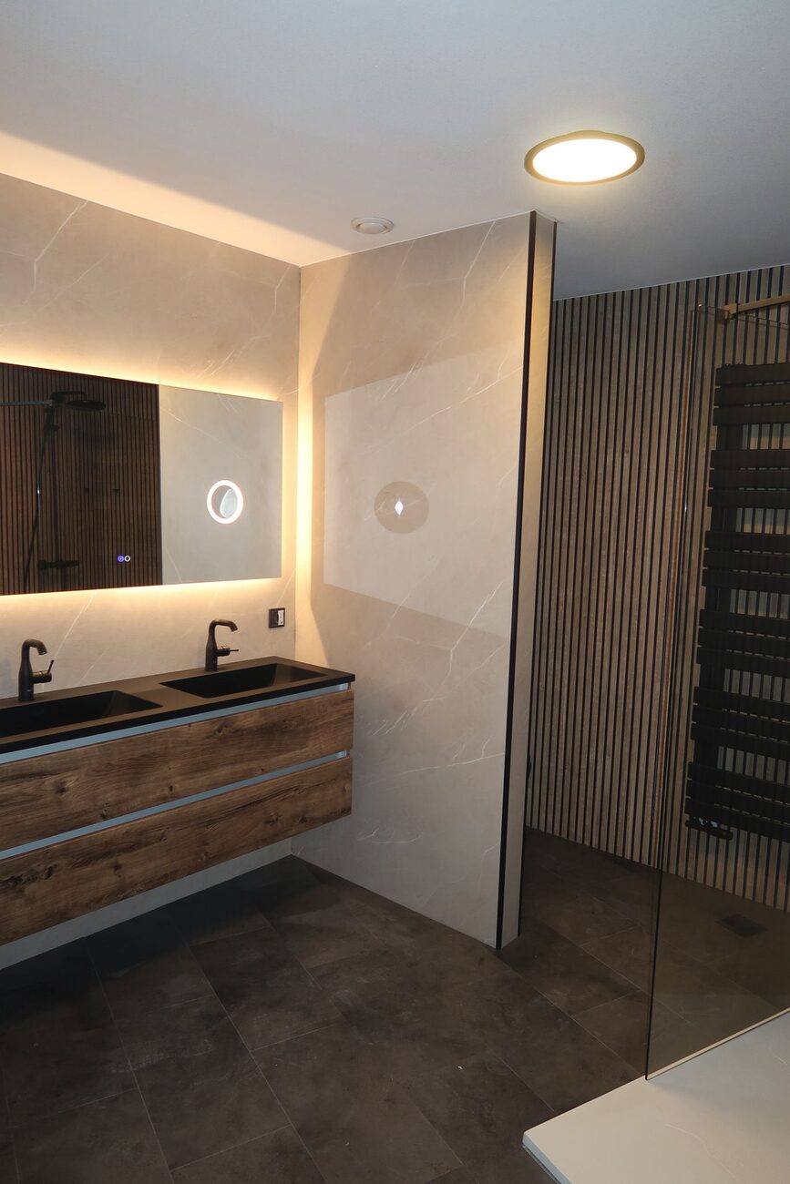 Moderne badkamer met houten wastafelmeubel, lichte wandtegels en inloopdouche.