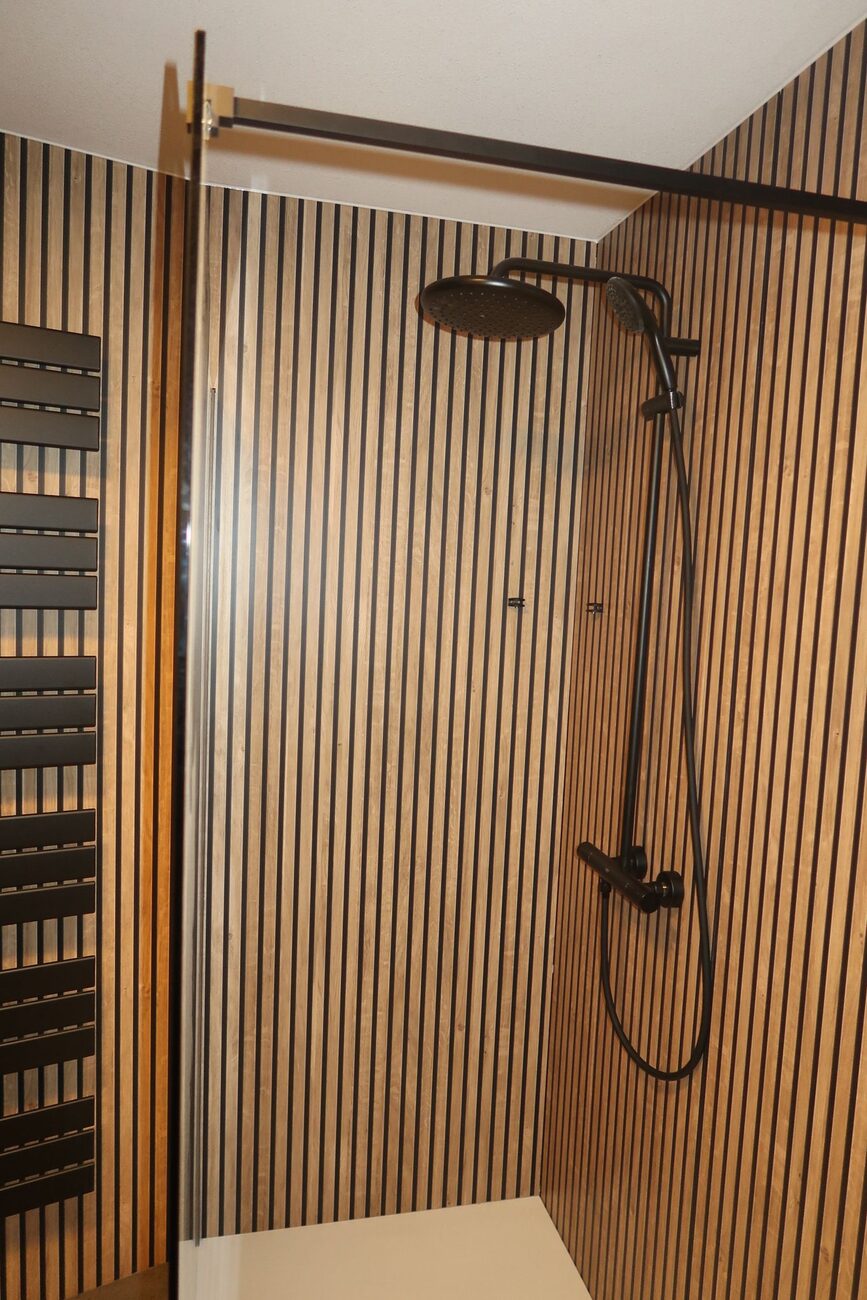 Moderne badkamer met houten lattenwand en zwarte douche