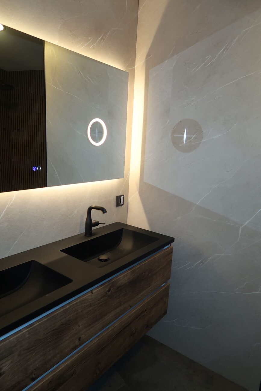 Moderne badkamer met dubbele wastafel, houten meubel en verlichte spiegel