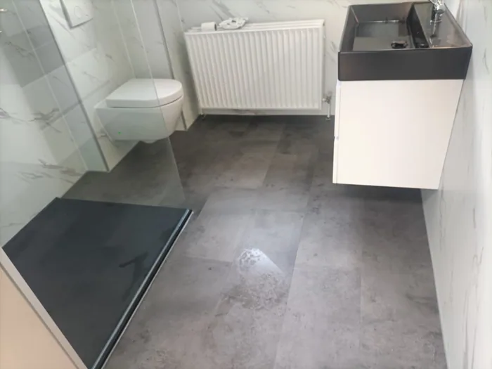 Gerenoveerde badkamer met inloopdouche, glazen wand, hangtoilet, wit wastafelmeubel met zwarte waskom en marmerlook wanden