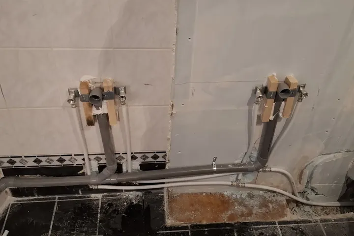 Nieuwe waterleidingen met aansluitpunten op de wand, onderste tegelrand en zwarte vloer