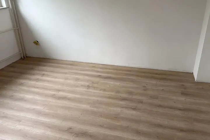 Lege kamer met witte muren en nieuwe houtlook laminaatvloer