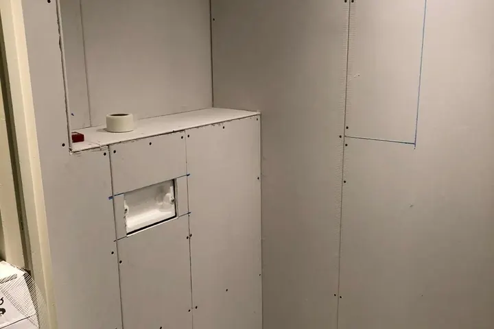 Toiletruimte tijdens renovatie: nieuwe voorzetwand met plank, opening voor bedieningsplaat en aansluitingen voor hangtoilet