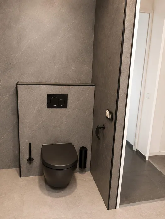 Zwart hangtoilet tegen grijze voorzetwand met zwart bedieningspaneel