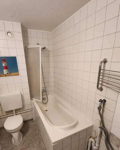 Badkamer vóór de verbouwing: ligbad met douchescherm naast het toilet