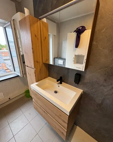 Dezelfde badkamer na de renovatie met wandpanelen, eiken badmeubel en spiegelkast
