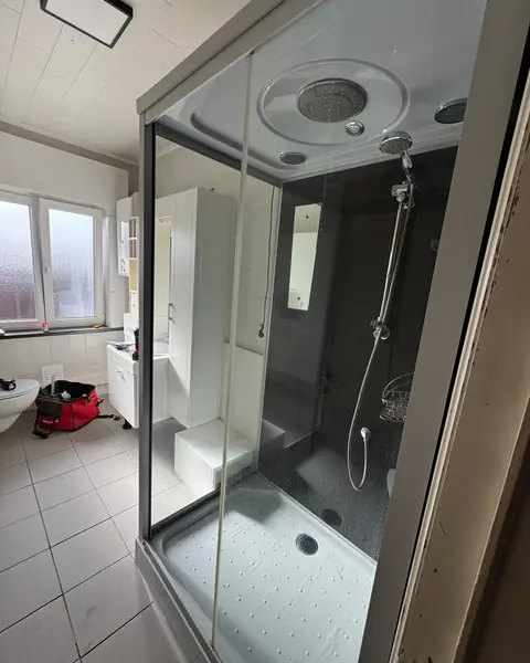 Badkamer vóór de renovatie met een oude douchecabine